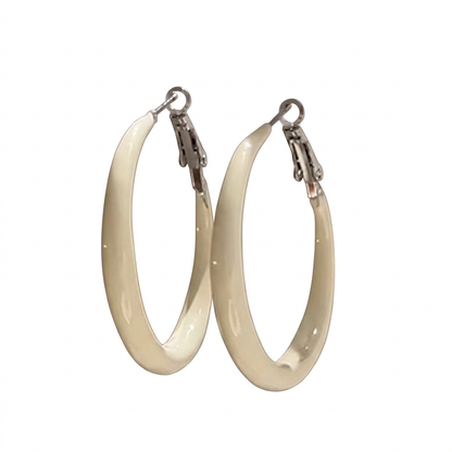 Para kremowych kolczyków kółek ze srebrnymi zapięciami na białym tle